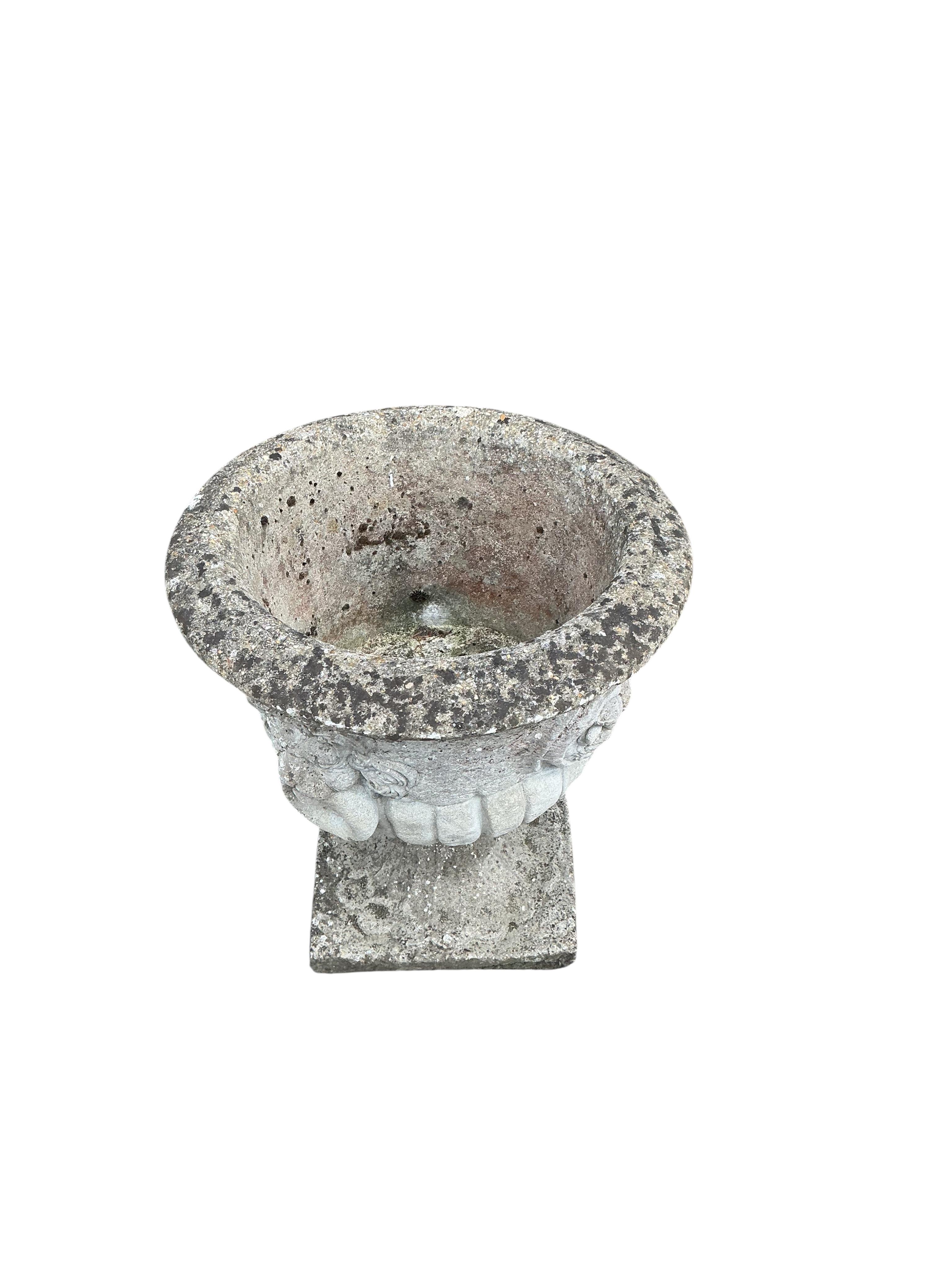 A pair of circular reconstituted stone garden urns with moulded lion mask ring decoration, diameter 53cm, height 60cm